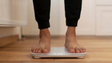 Donna che utilizza una bilancia impedenziometrica per misurare la composizione corporea