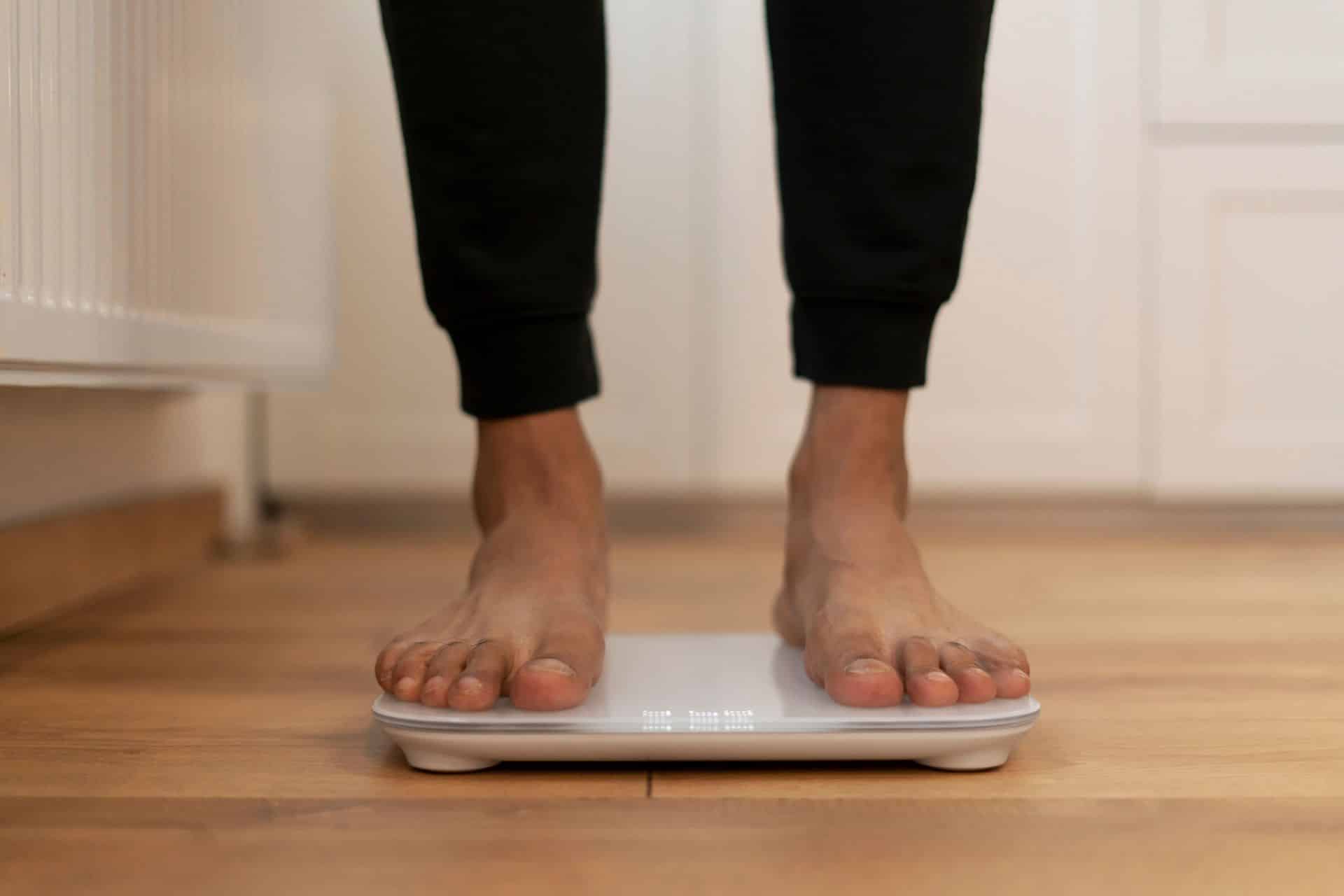 Donna che utilizza una bilancia impedenziometrica per misurare la composizione corporea